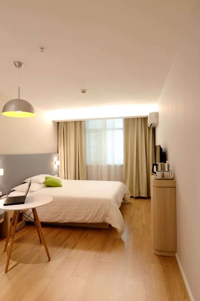 Spacious modern hotel room featuring cozy decor and neutral tones with natural light.